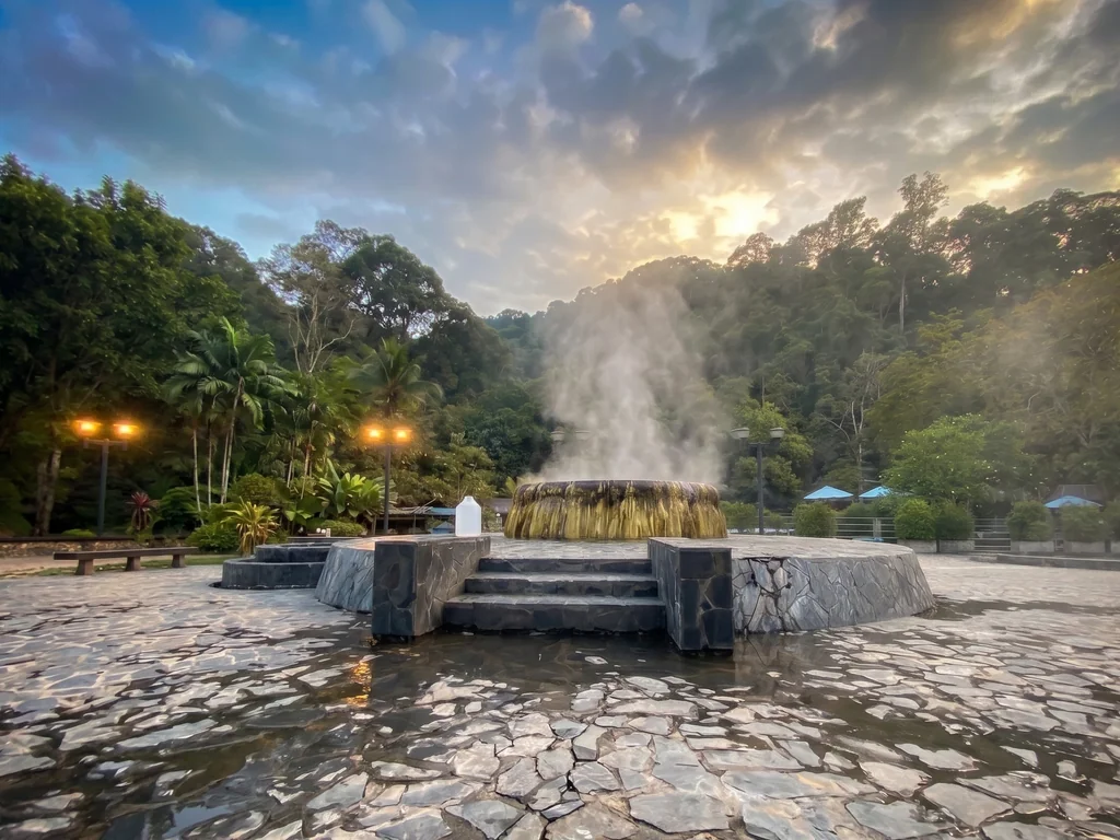 Steam rising from Raksa Warin Hot Springs in a forested setting in Ranong